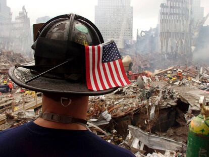 Un bombero con una bandera estadounidense en el casco, contempla las ruinas de las Torres Gemelas, sede del  World Trade Center, en Nueva York (Estados Unidos), casi un mes después de los atentados terroristas contra Nueva York y Washington.
