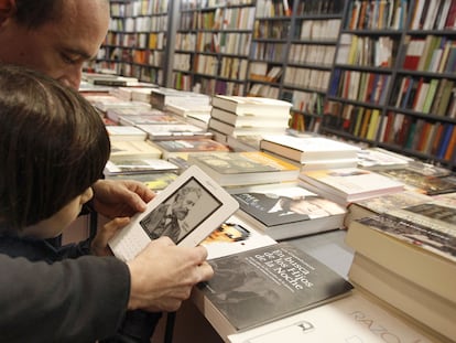 Dos lectores consultan un libro digital en una librería tradicional.