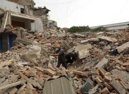 Dos personas buscan cadáveres entre los escombros de casas destruidas.