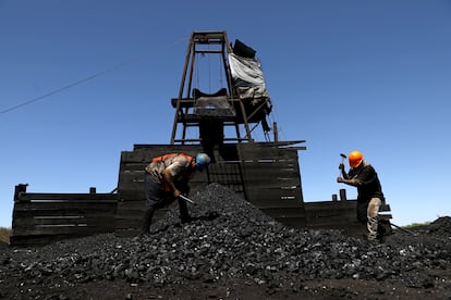 Dos obreros parten trozos de carbón a las afueras de una mina, el 25 de marzo de 2021.