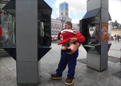 Un hombre vestido de Super Mario utiliza una cabina de teléfonos en la Puerta del Sol de Madrid.