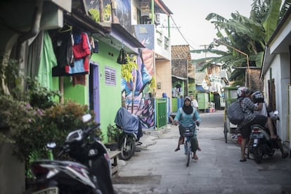 Una vecina pasea en bici en el kampung Kedondong, decorado con murales por el grafitero indonesio X-Go, que lucha por “embellecer los barrios de los que no pueden vivir en torres”.