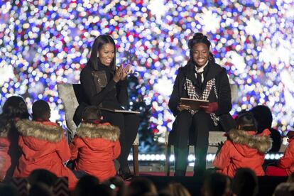 La primera dama de Estados Unidos, Michelle Obama lee el libro "Cuento De Nochebuena" a un grupo de niños junto a la nadadora olímpica Simone Manuel.