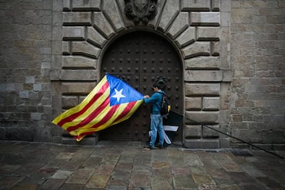 Un joven prepara su bandera estelada junto a una de las puertas laterales del Palau de la Generalitat de Barcelona, este miércoles.