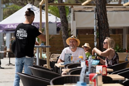 Un camarero sirve a unos clientes en una terraza en Platja d'Aro (Girona).