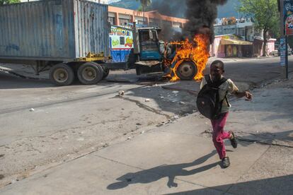 Un manifestante huye de un camión en llamas durante una manifestación, este lunes, en Puerto Príncipe (Haití). La marcha estaba convocada por la muerte del estudiante Grégory Saint-Hilaire quien falleció, presuntamente, a causa de los tiros de un policía de la guardia presidencial el pasado 2 de octubre. Las protestas coinciden con una advertencia hecha este lunes por el Consejo de Seguridad de la ONU por el riesgo de que estas tensiones desestabilicen Haití.