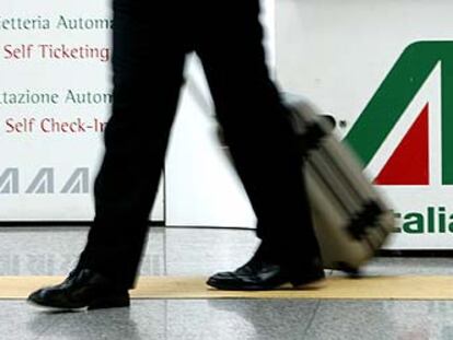 Un pasajero camina delante del emblema de Alitalia en el aeropuerto de Fiumicino (Roma).