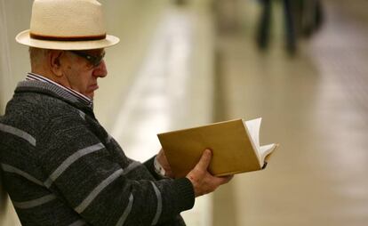 Un hombre lee un libro en una calle de Barcelona.