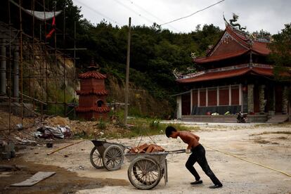 Worker Shi Shenwei pushes a wheelbarrow at the construction site of a Buddhist temple in the village of Huangshan, near Quanzhou, Fujian Province, China, September 27, 2016. REUTERS/Thomas Peter        SEARCH "BRICK CARRIER" FOR THIS STORY. SEARCH "WIDER IMAGE" FOR ALL STORIES. 