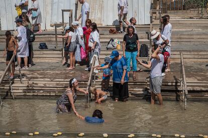 Un peregrino es bautizado mientras el resto del grupo saca fotografías. Tanto en la orilla oriental como en la occidental del río hay varios sitios bautismales dónde se realizan rituales de fe, lo que refleja la importancia histórica y religiosa del lugar. Además, según el Antiguo Testamento, aquí se cumplieron más de 75 milagros, como el del profeta Elías, que fue alimentado por cuervos, o como el del rey Naamán, que fue curado de la lepra después de sumergirse siete veces en estas aguas.