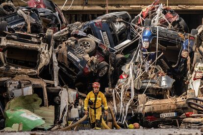 Un bombero rodeado de coches destrozados y apilados, entre Benetússer y Alfafar, este viernes.