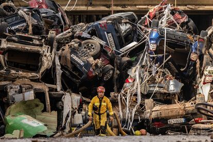 Un bombero rodeado de coches destrozados y apilados, entre Benetússer y Alfafar, este viernes. 