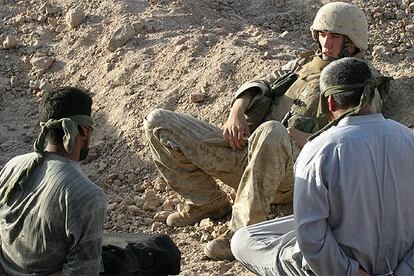 Un <i>marine</i> estadounidense vigila a dos presos iraquíes, maniatados y con los ojos vendados, capturados en Faluya.