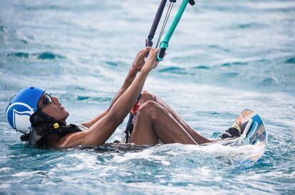 Barack Obama en el agua, agarrando el mástil de la vela de 'kite surf'.