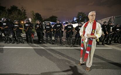 Un miembro frente a la línea de agentes de policía en Charlotte, la tercera noche de protestas.
