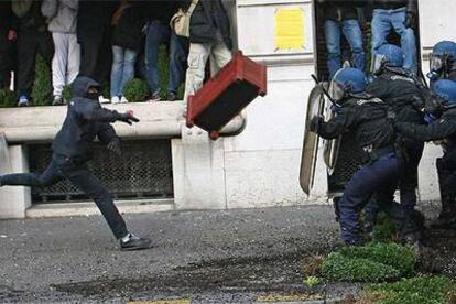 Un manifestante arroja una jardinera contra agentes antidisturbios de la policía tras la marcha de estudiantes de ayer en las calles de París.