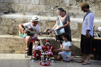 Unos turistas hablan con un músico en una calle del centro de Valencia.