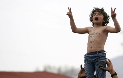 Uma criança protesta na fronteira entre Grécia e Macedonia pela falta de água e alimentos. "Nem água nem comida", diz o eslogan pintado no peito.