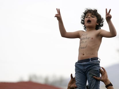 Uma criança protesta na fronteira entre Grécia e Macedonia pela falta de água e alimentos. "Nem água nem comida", diz o eslogan pintado no peito.