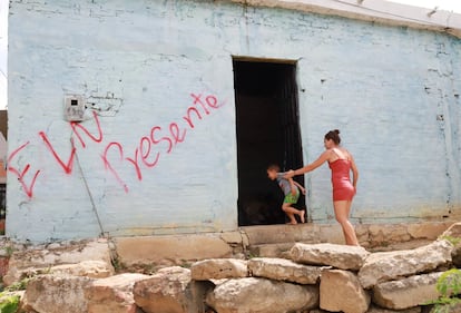 Una mujer y un niño entran a una casa marcada con un grafiti del ELN en Cúcuta (Colombia), en julio de 2023.