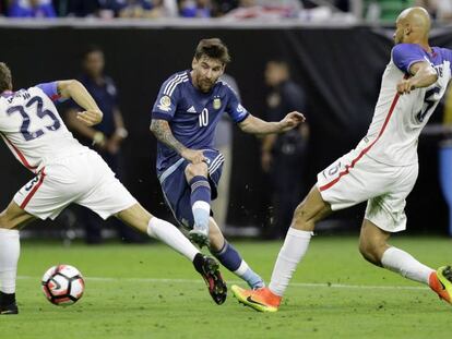 Messi chuta no meio de dois norte-americanos.