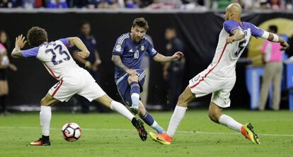 Messi chuta no meio de dois norte-americanos.