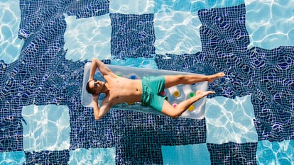 Un hombre en una colchoneta dentro de una piscina.