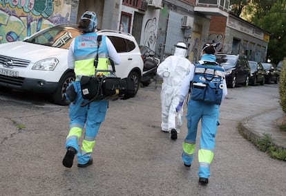 El técnico Andrés, a la izquierda, la médica Marta Calvo (traje blanco) y la enfermera Vanesa Jiménez, en una calle de Madrid, camino de un aviso. 