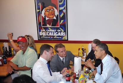 Como otros dos clientes más del local, los presidentes comen sus hamburguesas. Mientras, en la mesa colindante, una mujer intenta hacer una foto a los dos líderes.