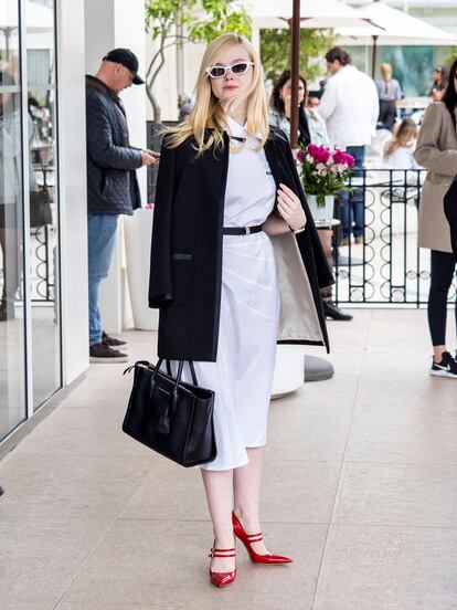 Aquí Elle combina un vestido blanco de Miu Miu con chaqueta negra y bolso de Prada. El toque de color lo dan sus zapatos rojos.