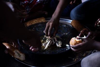 Los hijos de Selma, beneficiaria del programa de mejora de la seguridad alimentaria, comparten el plato de pescado que acompañan con un poco de pan.