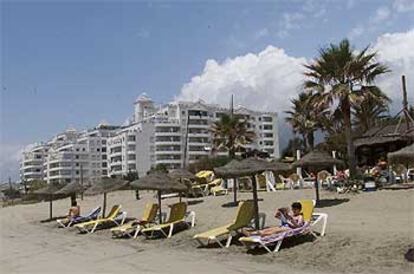 Residentes en Banana Beach toman el sol junto a la urbanización de Marbella.