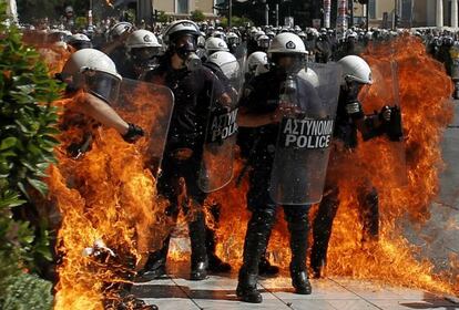 Un grupo de polic&iacute;as rodeados por el fuego causado por una bomba Molot&oacute;v.