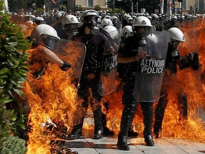 Un grupo de policías rodeados por el fuego causado por una bomba Molotóv.