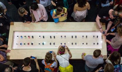 Un grupo de clientes rodea un mostrador de Apple Watch en una tienda de Mosc&uacute;.