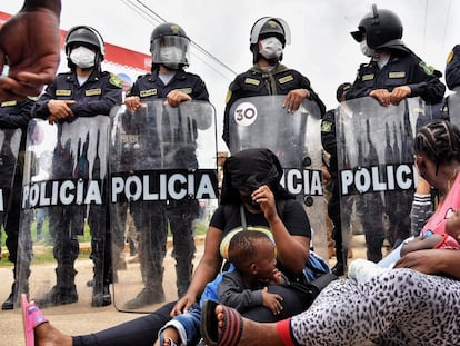 Duas mães migrantes diante do bloqueio policial na cidade peruana de Iñapari, na fronteira com o Brasil, na quinta-feira.