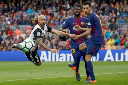 El delantero italiano del Valencia, Simone Zaza (i), intenta un remate ante el centrocampista del Barcelona, Sergio Busquets (d) y el defensa francés Samuel Umtiti (c).