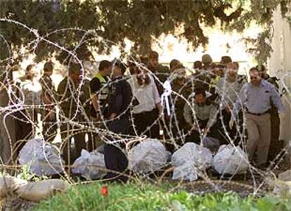 Policías israelíes, junto a los cadáveres de los soldados muertos ayer en un puesto de control del Ejército israelí.