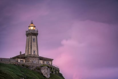 Vista del asturiano faro de Avilés, también conocido como faro de Nieva, con su luminaria encendida al atardecer.