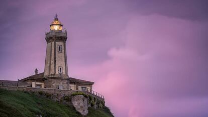 Vista del asturiano faro de Avilés, también conocido como faro de Nieva, con su luminaria encendida al atardecer.