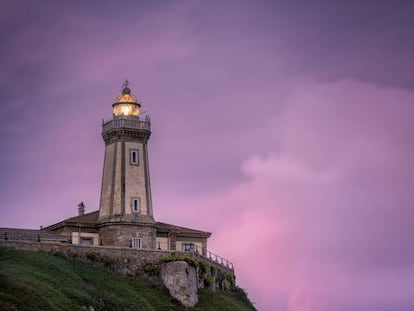 Vista del asturiano faro de Avilés, también conocido como faro de Nieva, con su luminaria encendida al atardecer.