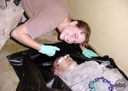 La soldado Sabrina Harman sonríe junto al cadáver de un preso iraquí en la prisión de Abu Ghraib.