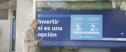 Una persona pasa por delante de una sucursal de BBVA en la que se anuncian planes de pensiones. 