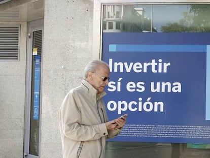 Una persona pasa por delante de una sucursal de BBVA en la que se anuncian planes de pensiones. 