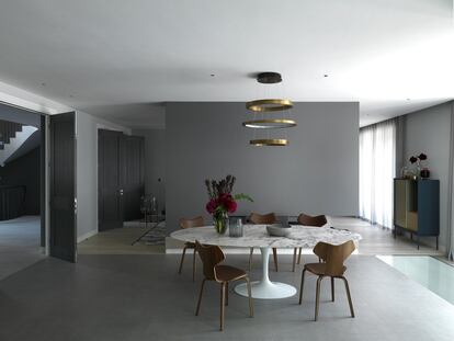 Entre la cocina y el salón, el comedor está amueblado con una mesa oval con sobre de mármol diseñada por Eero Saarinen y producida por la empresa Knoll. Las sillas son el modelo Grand Prix de Arne Jacobsen (Fritz Hansen) forrado en piel. La lámpara de latón es de Henge, la alfombra fue tejida a mano en Nepal (CC-Tapis) y la lámpara de suelo es el modelo Oda producido por la alemana Pulpo.