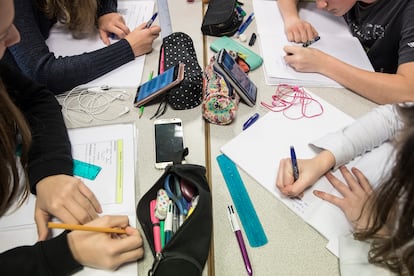 Un grupo de niños hace las tareas de clase con el móvil sobre la mesa.