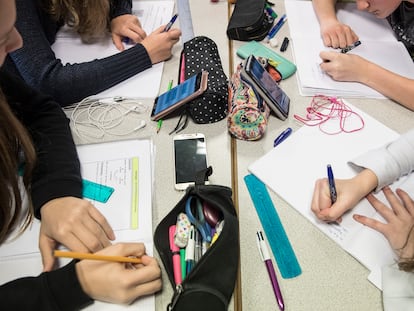 Un grupo de niños hace las tareas de clase con el móvil sobre la mesa.