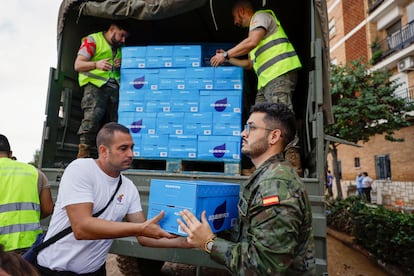 Vecinos de Paiporta reciben agua repartida por el Ejército este viernes.