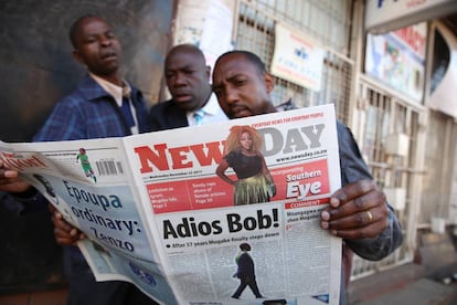 Tres hombres leen el periódico en una calle en Harare este miércoles.