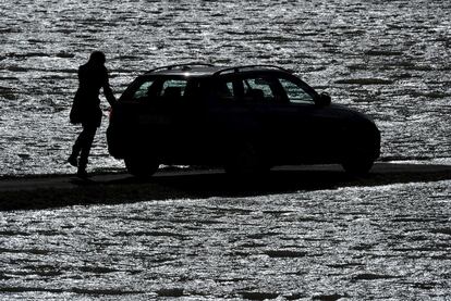 Una persona, fotografiada al lado de su coche en una carretera casi completamente inundada en Bunsendorf, Alemania.